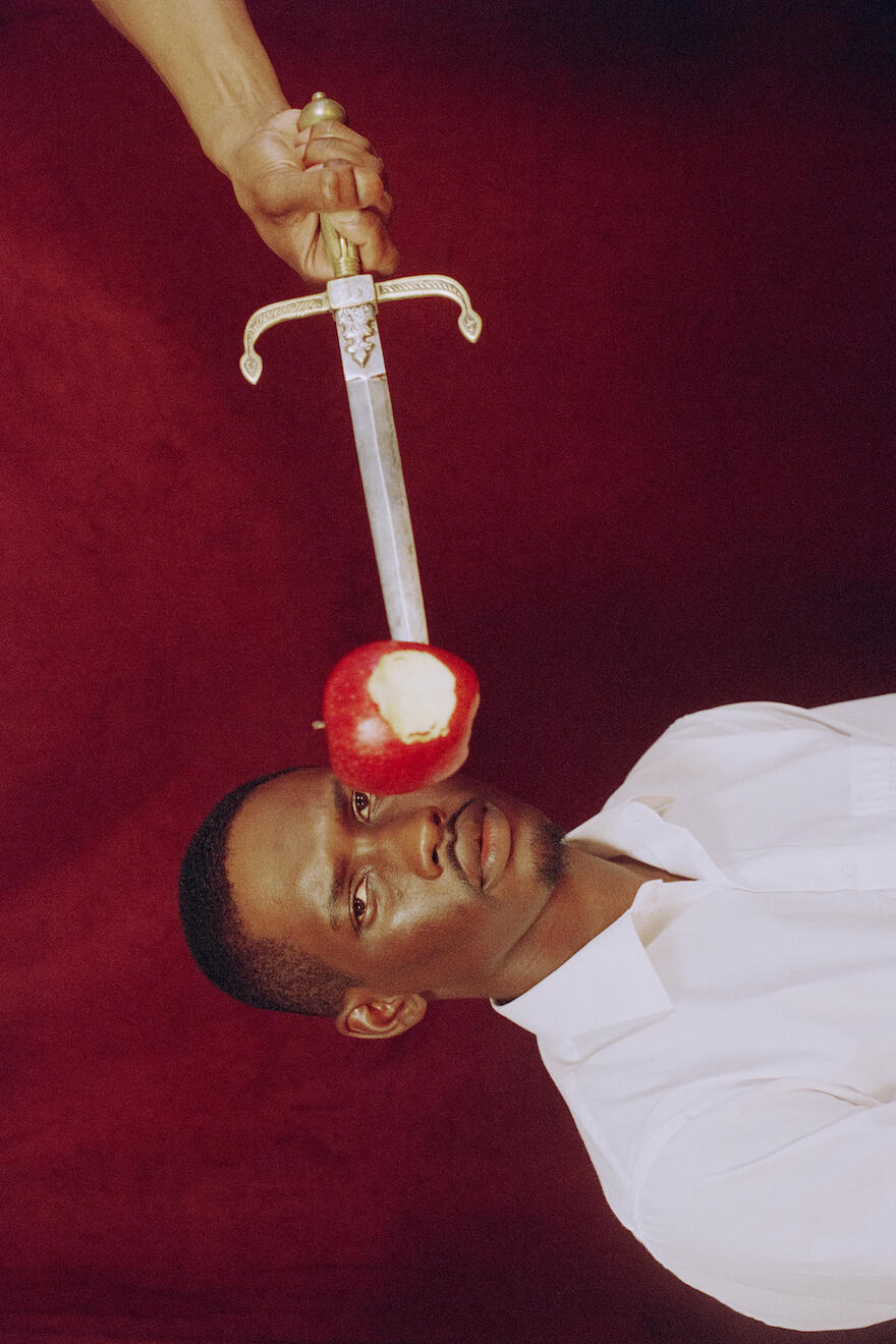 Man being offered an apple with a sword